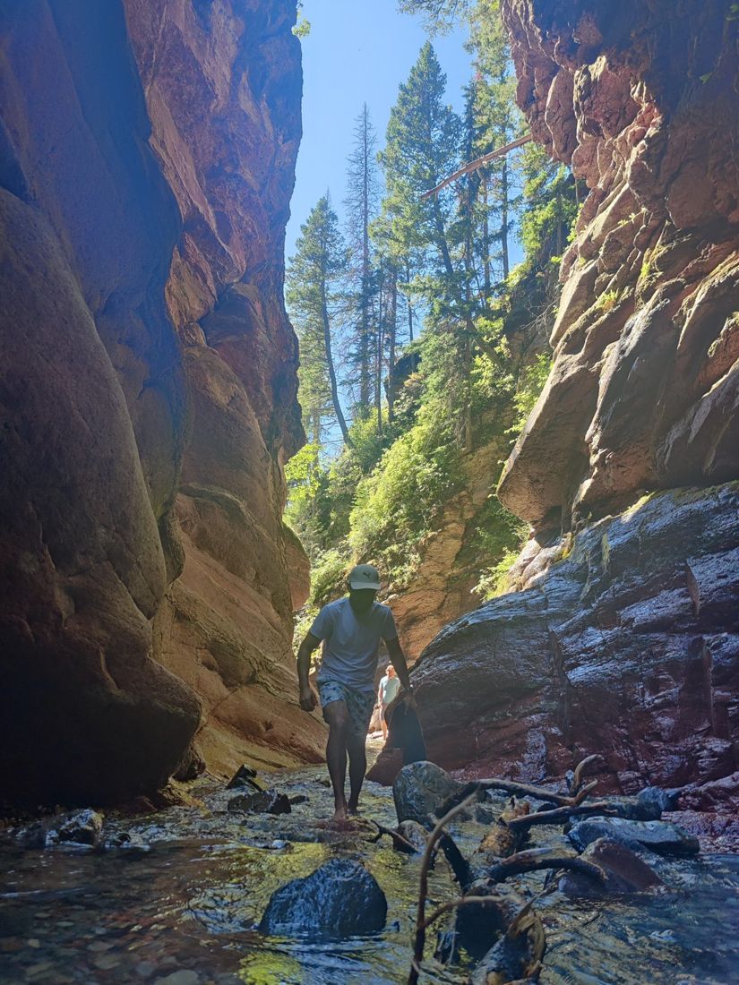 Wading through shallow water in a narrow red rock canyon